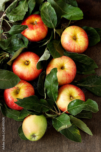 Fresh red apples with green leaves on wooden table