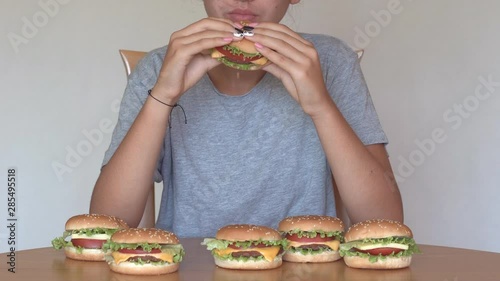 Hungry girl eating fastfood hamburger. Unhealthy eating