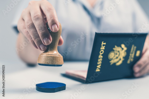 Immigration and passport control at the airport. woman border control officer puts a stamp in the US passport of american citizen. Concept photo