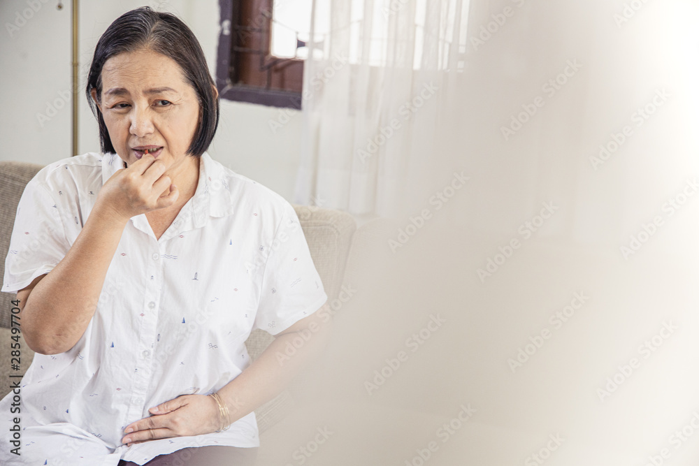 old age, health problem, vision and people concept - close up of Asian senior woman sitting on sofa and having headache at home.She may had Headache Symptoms.She looks pain and sick old age, health problem, vision and people concept - close up of Asian senior woman sitting on sofa and having headache at home.She may had Headache Symptoms.She looks pain and sick