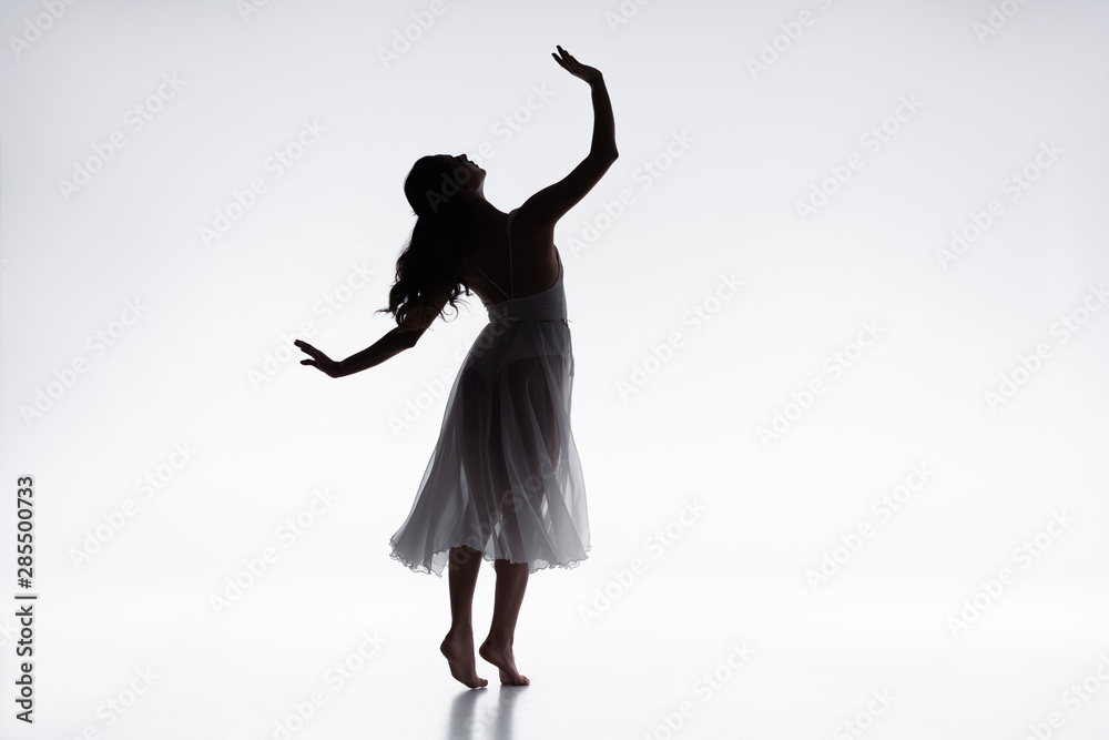 graceful, elegant ballerina in white dress dancing on grey background graceful, elegant ballerina in white dress dancing on grey background
