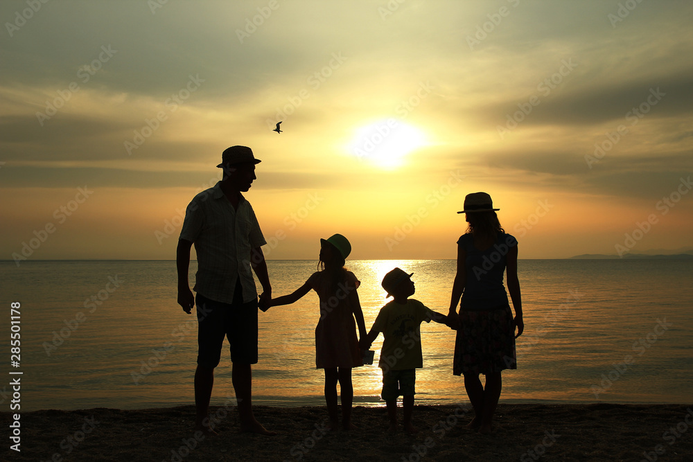 family silhouette at sunset by the sea