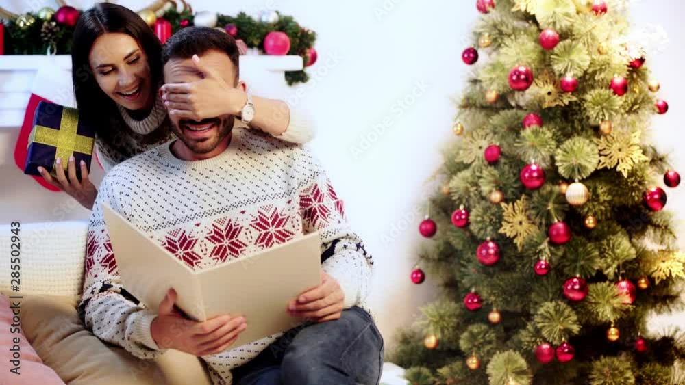 wife covering eyes of husband and giving present wife covering eyes of husband and giving present
