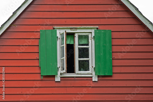 Window with green sun blinds on the red wall of wooden Scandinavian style house  Norway