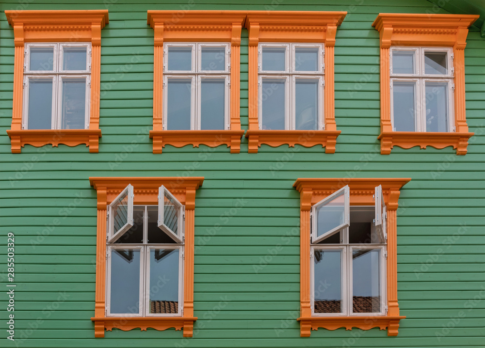 Orange windows on the green wall of green wooden house, Stavanger, Norway