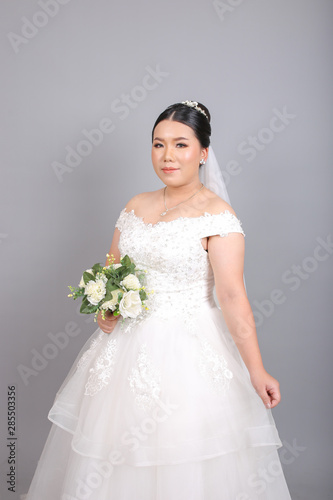 Fat Asian bride holding a bouquet of flower in studio