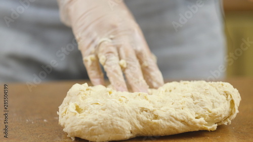 woman mother or daughter on the kitchen table makes domestic food pizza, hands work and pushing stir knead the dough, selective focus dolly shot