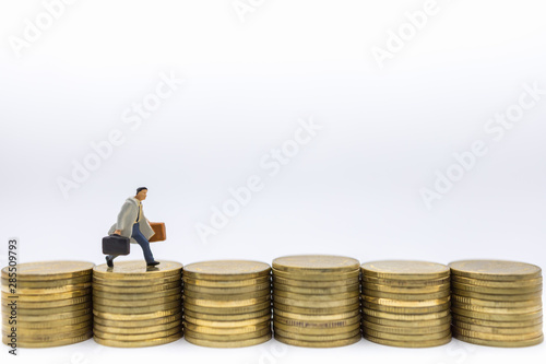 Business, Money, Finance and management concept. Close up of businessman miniature figure with baggage running on top of row of stack of gold coins.