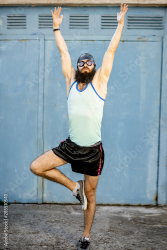 Portrait of a weird, old-fashioned swimmer dressed in 80s style with hat and swimming glasses on the yellow background photo