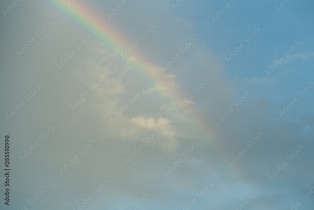 Rainbow with clouded blue sky background
