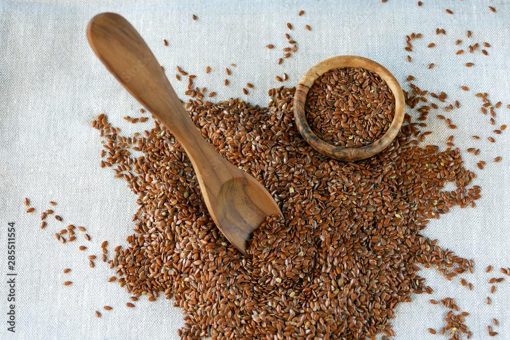 Flax seeds Linum usitatissimum - a useful and medicinal product. Close-up. Spoon and plate of natural olive tree among flax seeds..Product for beauty and health. Proper nutrition. Flax seeds Linum usitatissimum - a useful and medicinal product. Close-up. Spoon and plate of natural olive tree among flax seeds..Product for beauty and health. Proper nutrition.