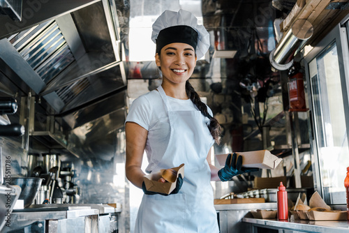 happy asian chef holding carton plates in food truck photo