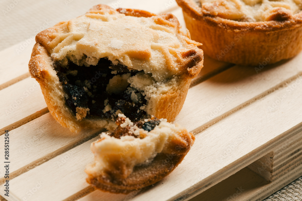 Two mince pies on the wooden surface with broken off piece Two mince pies on the wooden surface with broken off piece