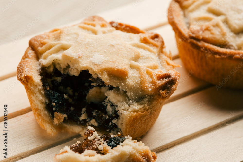 Blueberry mince pie with broken off piece on wooden board Blueberry mince pie with broken off piece on wooden board