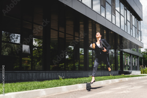 happy businesswoman levitating while holding briefcase and coffee to go © LIGHTFIELD STUDIOS