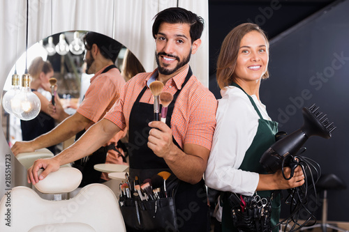 Smiling male makeup artist and woman hairdresser