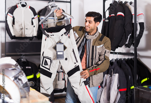 man is choosing new pants for motorbike in the moto store.