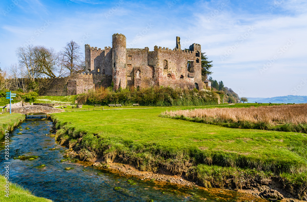 Ruins of the medieval Laugharne castle by a stream of water in Laugharne, Pembrokeshire, Wales, UK
