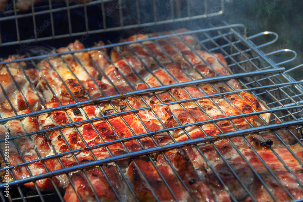 Grilled meat is cooked outdoors on the grill over an open fire or on a portable grill. Selective focus.