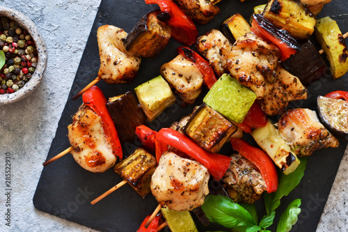 Barbecue of chicken on skewers with vegetables on stone background. Picnic.