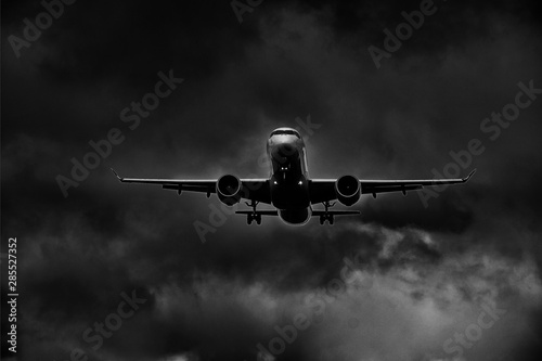 Airplane in landing approach with dark cloudscape