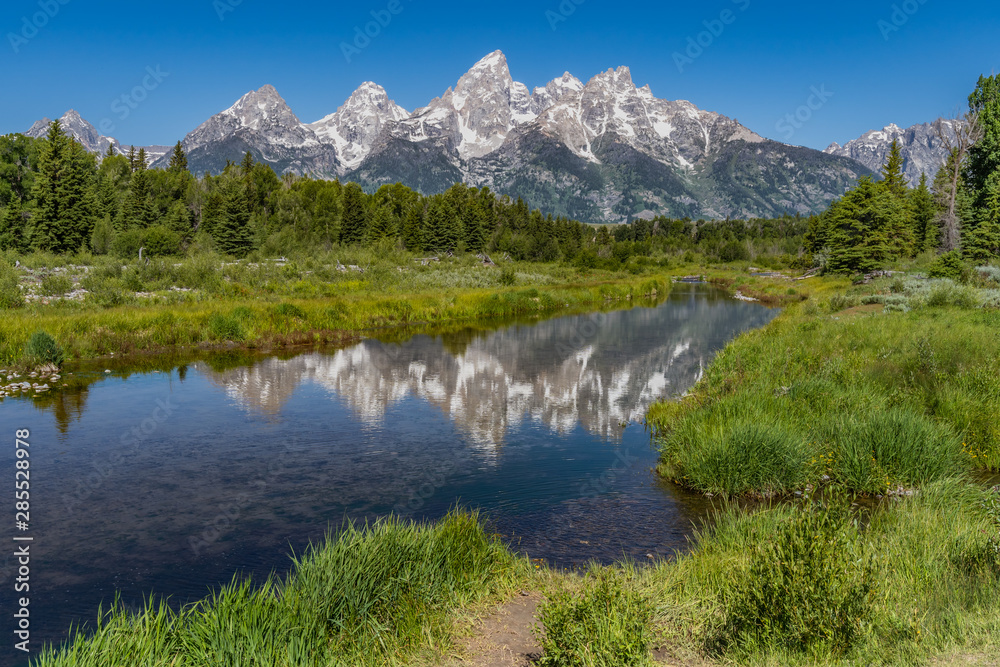 Schwabacher landing with river in the foreground and grand tetons in background mid summer blue sky