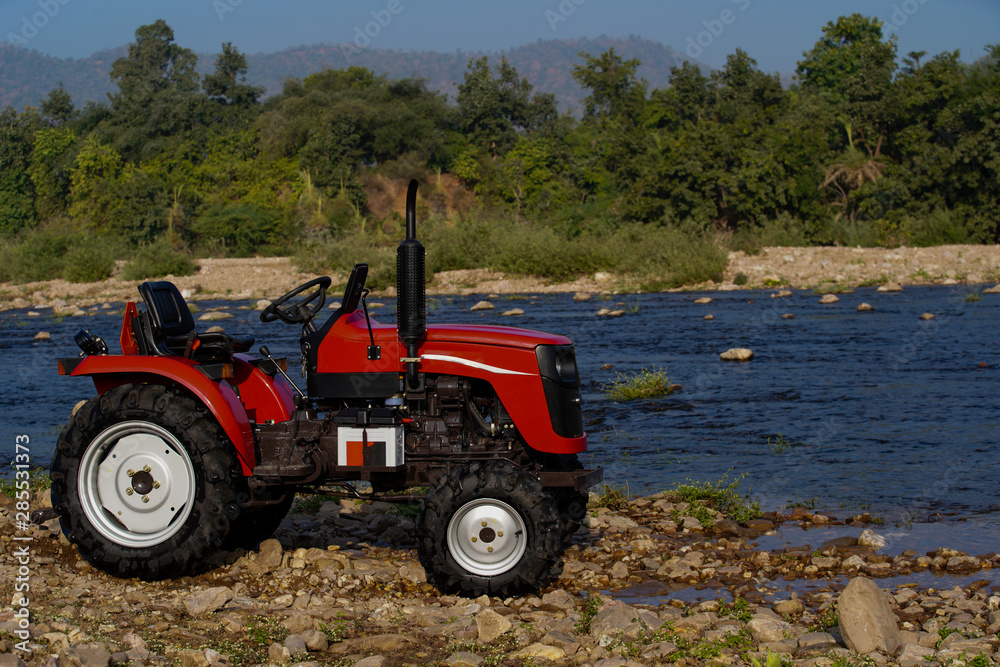 red tractor in the field on river bank red tractor in the field on river bank