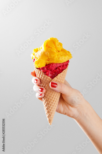 Fototapeta Woman hand holding ice cream cone on a neutral background
