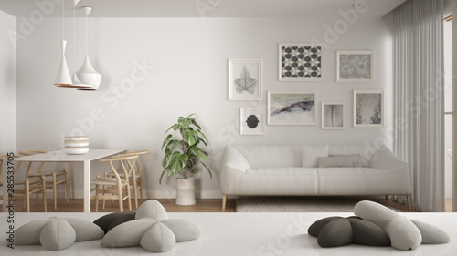 White table, desk or shelf with five soft white pillows in the shape of stars or flowers, over blurred modern living room, white architecture interior design concept