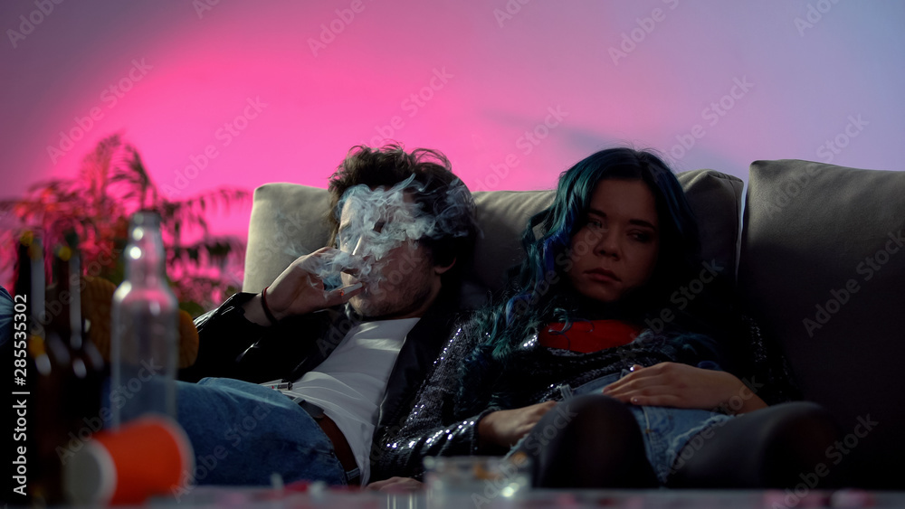 Φωτογραφία Drunk couple of druggies sitting on coach at home party in messy room, bad habit