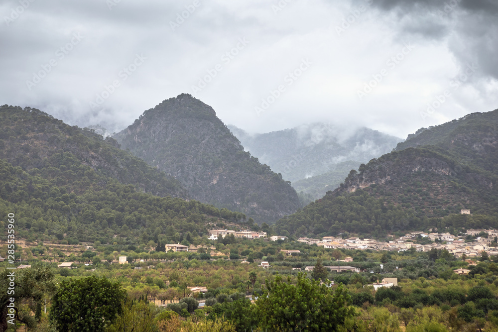 View of a small village with mountains in the fog as a background. Mallorca, Spain