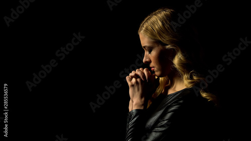 Miserable lady praying in darkness under heaven light, sinner confession, faith