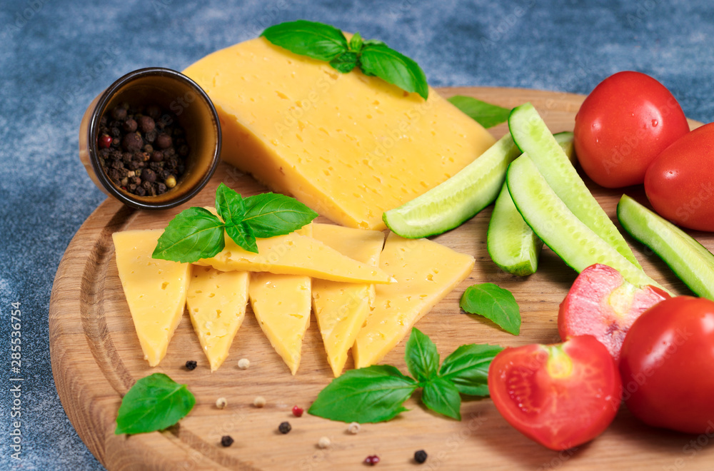 Dutch cheese with cucumbers and tomatoes and basil on a blue background