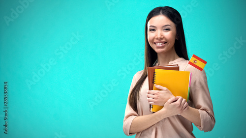 Cheerful woman holding Spanish flag book, education abroad, learning language photo