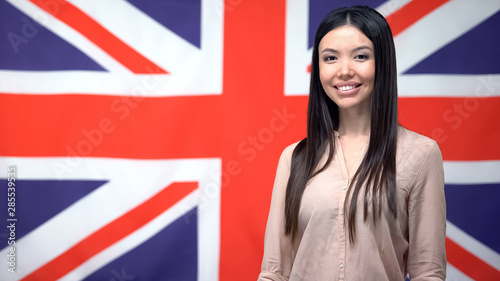 Pretty lady standing against British flag background, international cooperation