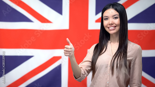 Beautiful woman showing thumbs-up against British flag background, template