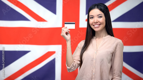 Female holding credit card against British background, international banking