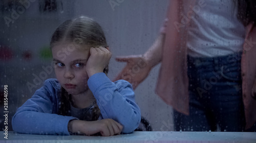 Mother scolding little girl behind rainy window, bad behavior in school, problem