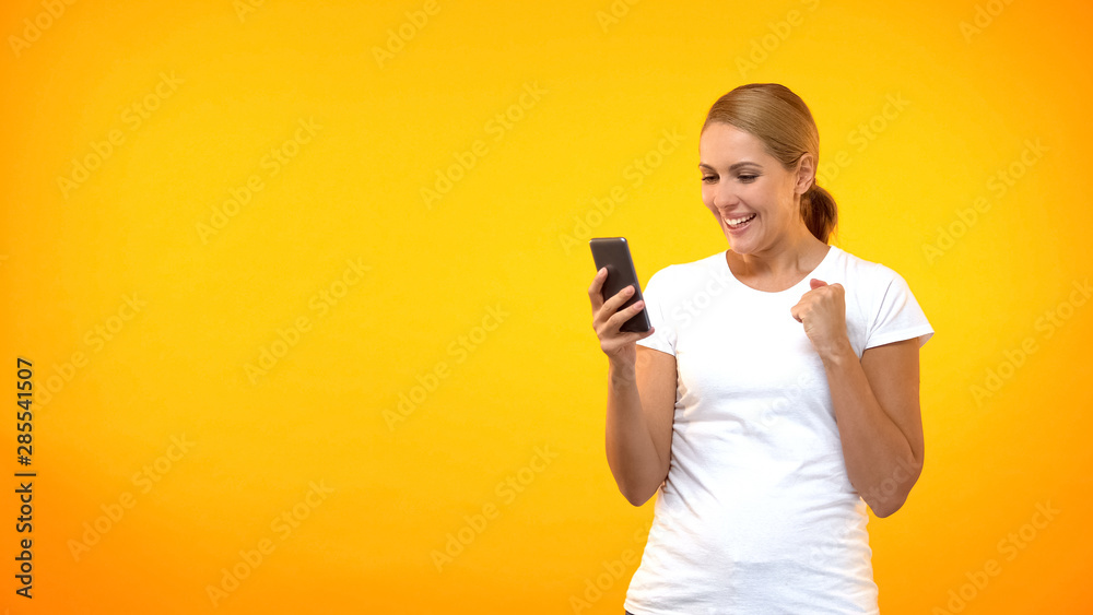 Excited female showing success gesture reading smartphone message, job offer