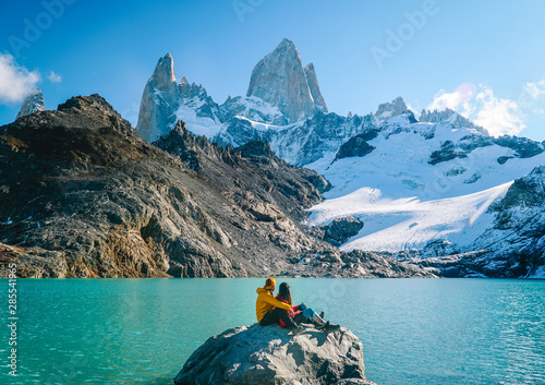 Couple in love at Mount Fitzroy. Scenic view of snowcapped mountain tops of Patagonia trek. Blue sky, turquoise lake and scenic rock landscape. Shot in Argentina. Nature, travel, adventure, hiking.