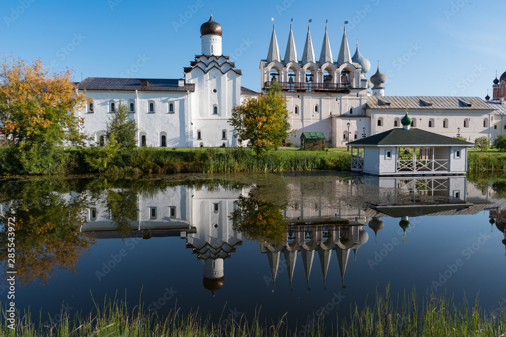 The bell tower of the Tikhvin Assumption (Bogorodichny Uspensky)   Monastery with a reflection in the pond. Tikhvin, Russia