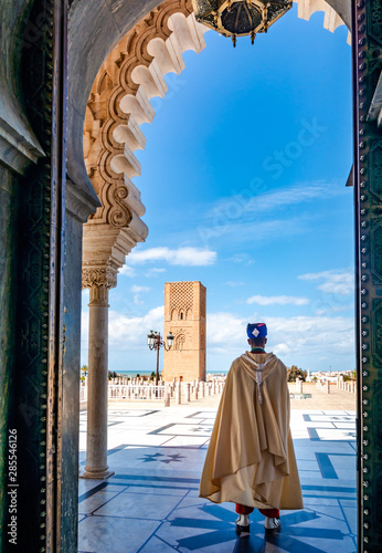 Guard soldier in national costume at the entrance of Mausoleum of Mohammed V and square with Hassan tower in Rabat on sunny day. Location: Rabat, Morocco, Africa photo