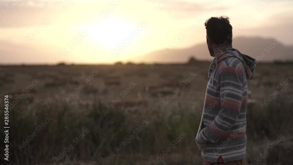 Young man looks out at sunset in field during summertime in Gibraltar, Spain Young man looks out at sunset in field during summertime in Gibraltar, Spain