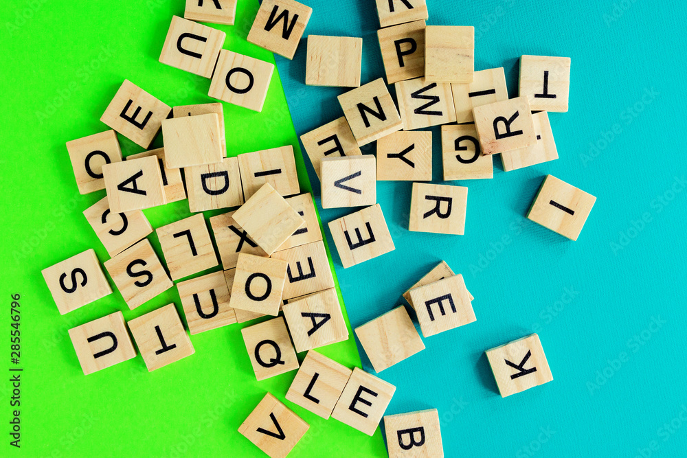 Pile of wooden letters on the surface of a green and blue background, selective focus Pile of wooden letters on the surface of a green and blue background, selective focus