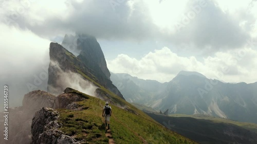 Traveler walking on the ridge of misty Seceda