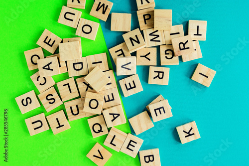 Pile of wooden letters on the surface of a green and blue background, selective focus