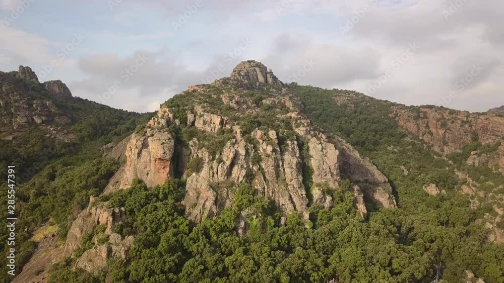 Drone panning around a beautiful roclky mountain with a blue sky in the background in Frejus France Drone panning around a beautiful roclky mountain with a blue sky in the background in Frejus France