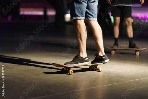 Photography of skateboarders'l legs, shoes and skate in night park. Skateboarder getting ready to do the trick to jump. Sportive lifestyles of youth. Dangerous risk speed sports.