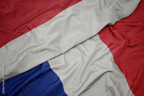 waving colorful flag of france and national flag of indonesia.