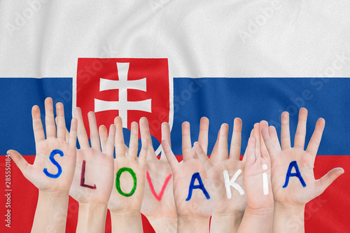 Inscription Slovakia on the children's hands against the background of a waving flag of the Slovakia photo